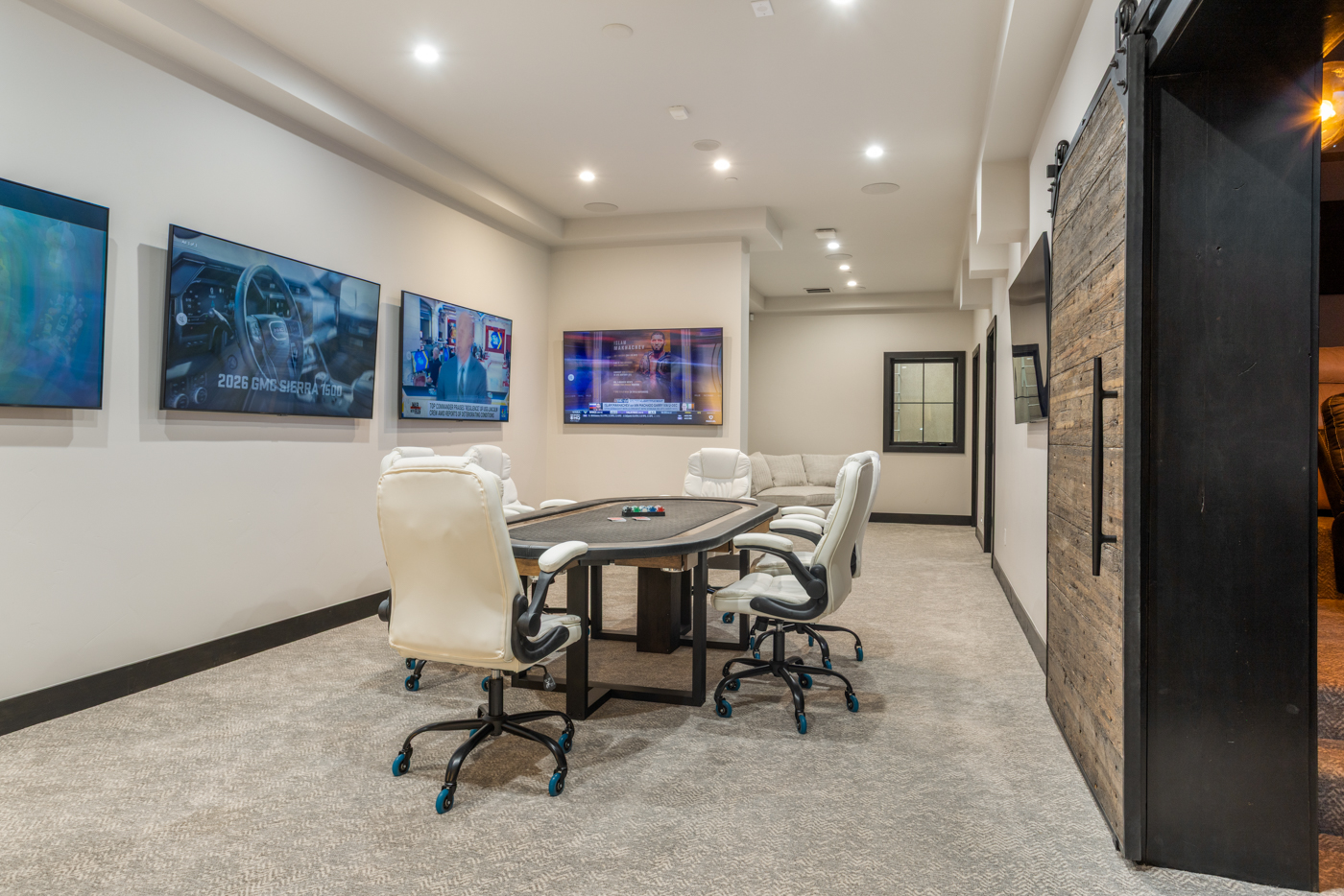 Game room with poker table, multi-screen wall, and reclaimed barn door