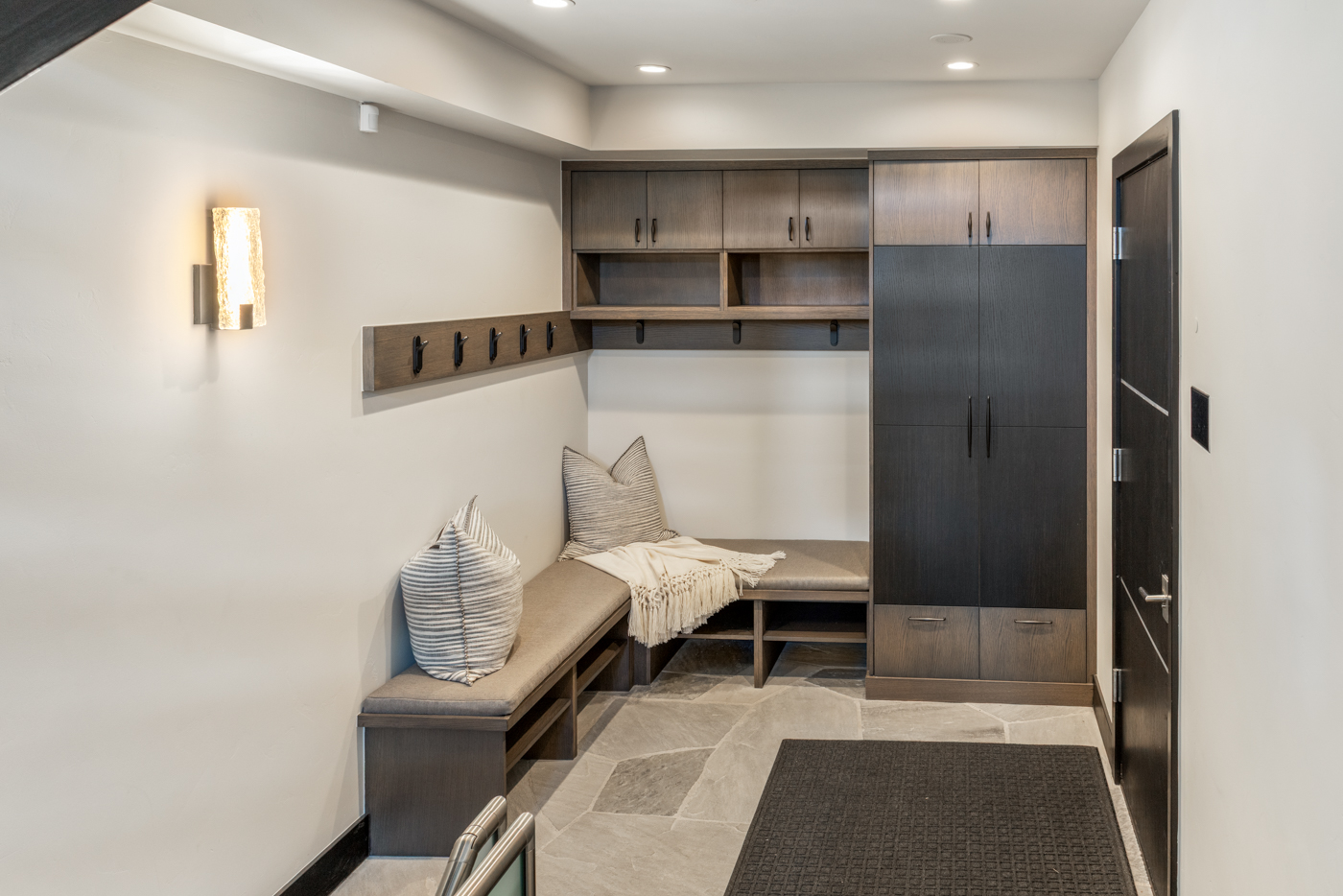 Mudroom with built-in bench, lockers, and stone floors