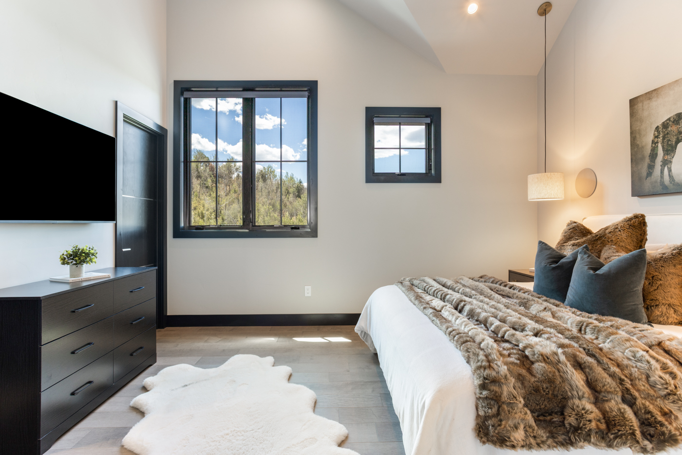 Guest bedroom with vaulted ceiling and forest views