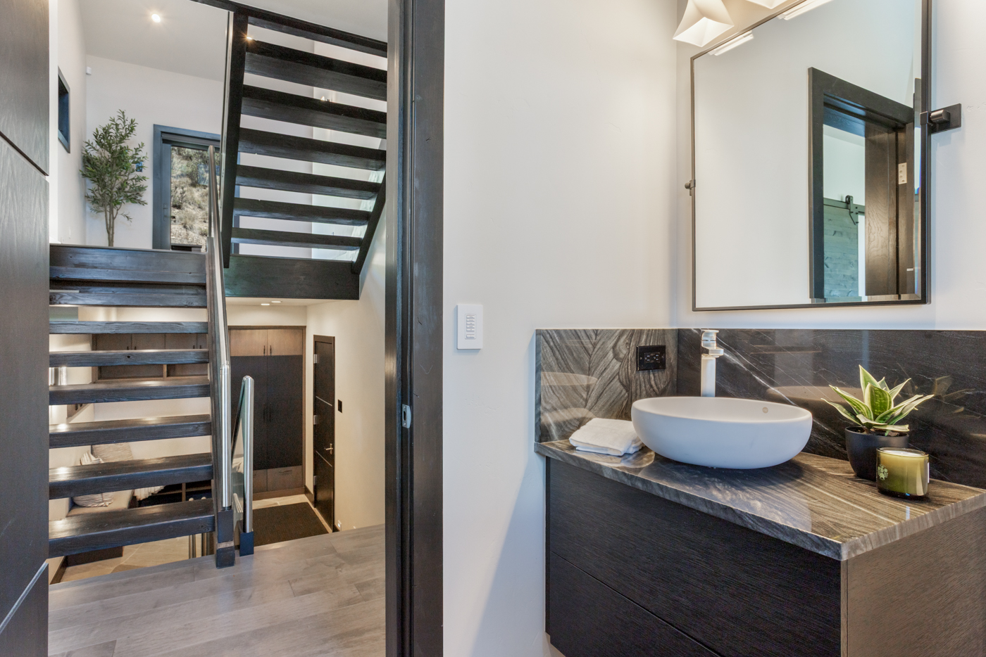 Powder bath with stone vanity beside the floating stair