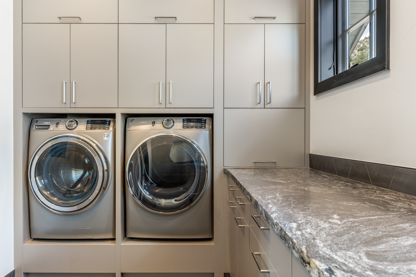 Laundry room with side-by-side machines and stone folding counter